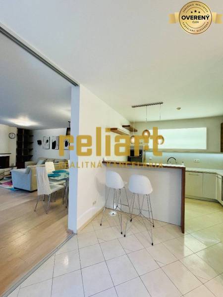A kitchen and living room in a family house with a bar counter and stools.