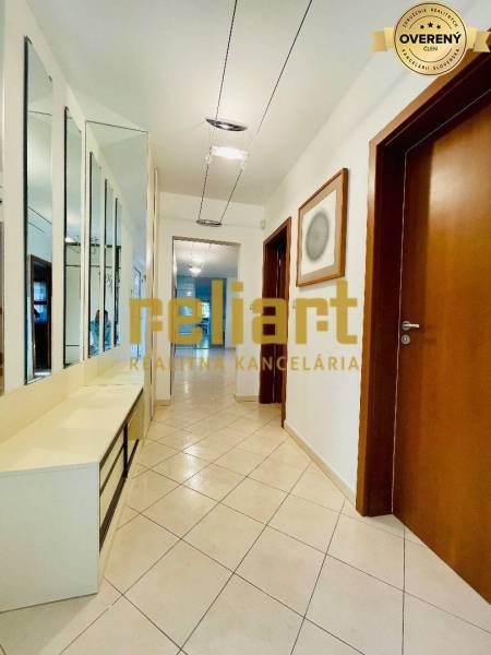 A hallway in a family house with tiles, a mirrored wall, and wooden doors.