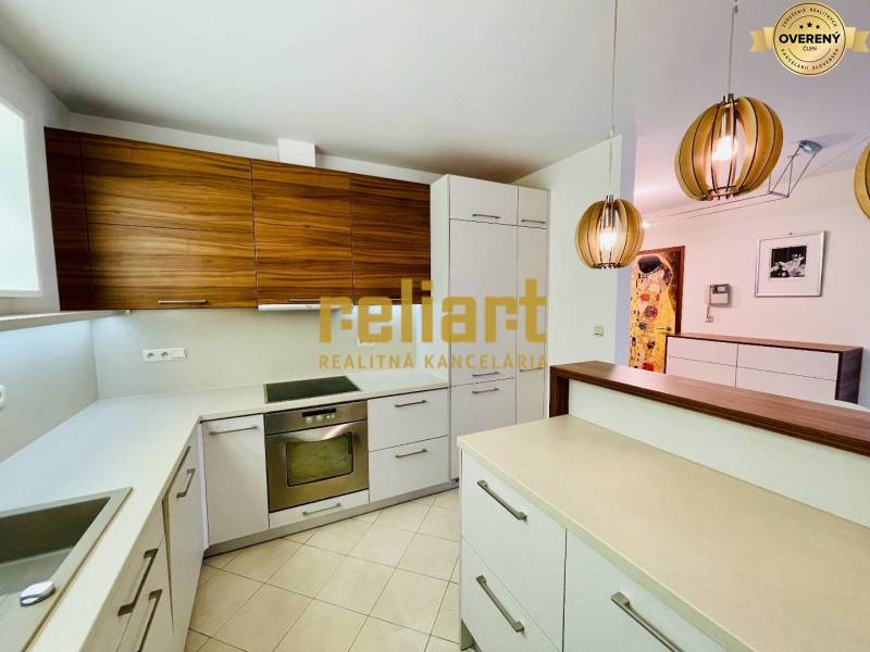 A kitchen in a family house with a kitchen unit, pendant lamps, and built-in appliances.