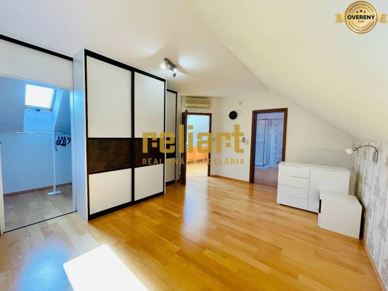 Attic room with wood-patterned flooring and a built-in wardrobe in a family house.