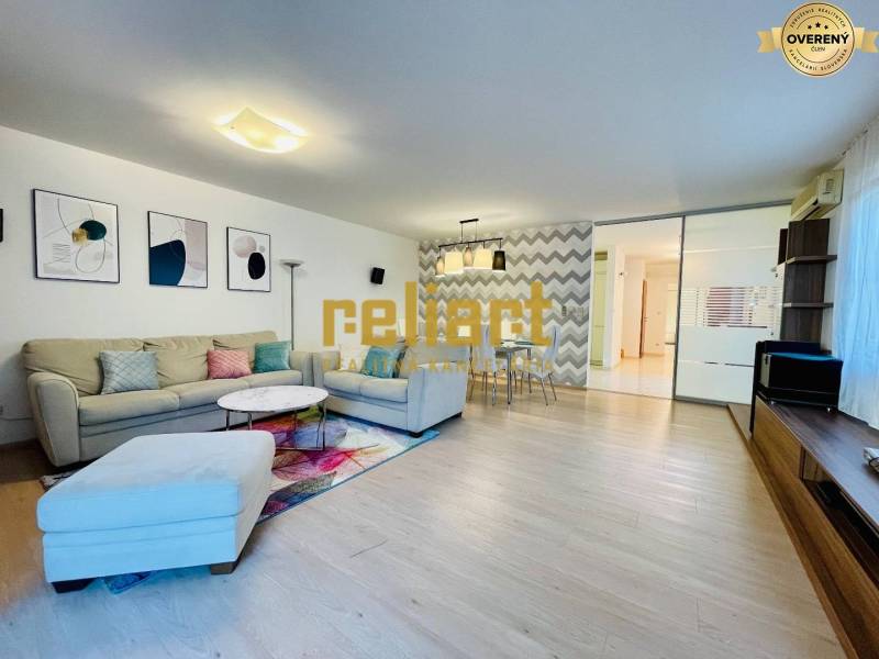 Living room in a family house with a sofa, decorations, and a wooden-patterned floor.