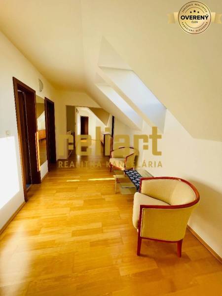 A hallway with a wooden decor floor, skylights, and comfortable armchairs in a family house.