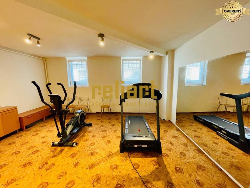Interior of a family house with a treadmill and an elliptical trainer on a floor with a wooden decor.