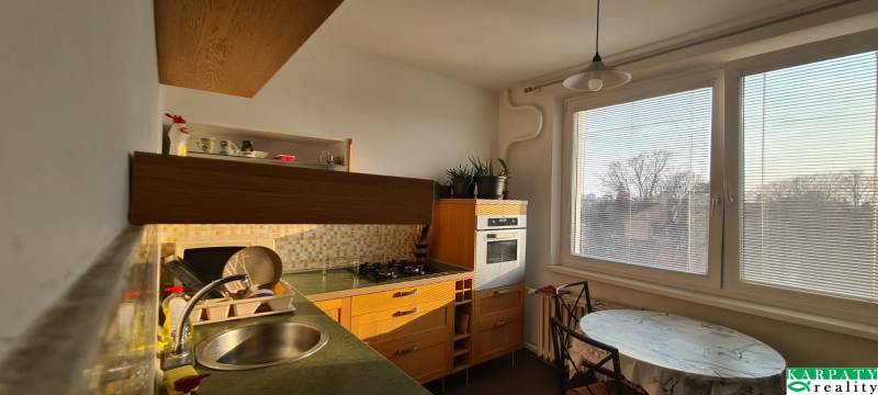 A kitchen with a gas stove, a window, and a table in a 3-room apartment.