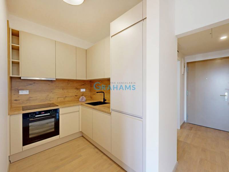 A kitchen in a 2-room apartment with a wooden decor floor and built-in appliances.