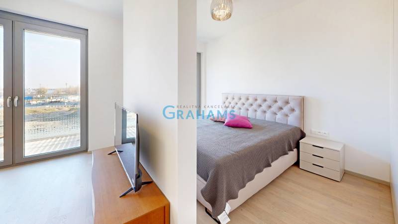 Double bedroom in a two-room apartment with wood-patterned flooring and a balcony.