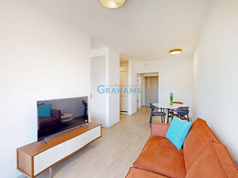 Living room with an orange sofa, dining table, and wooden decor flooring in a two-room apartment.