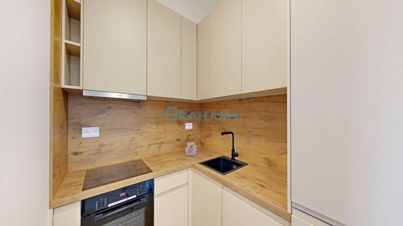 A kitchen in a 2-room apartment with a wooden decor, storage cabinets, and appliances.