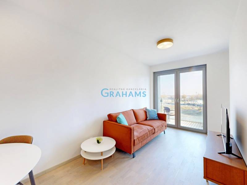 Living room in a two-room apartment with an orange sofa, TV, and balcony doors.