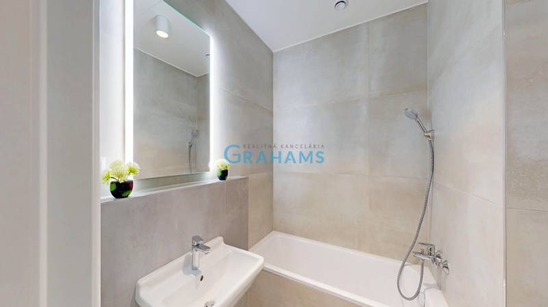 Bathroom in a 2-room apartment, with a bathtub and a sink, large mirror above the sink.