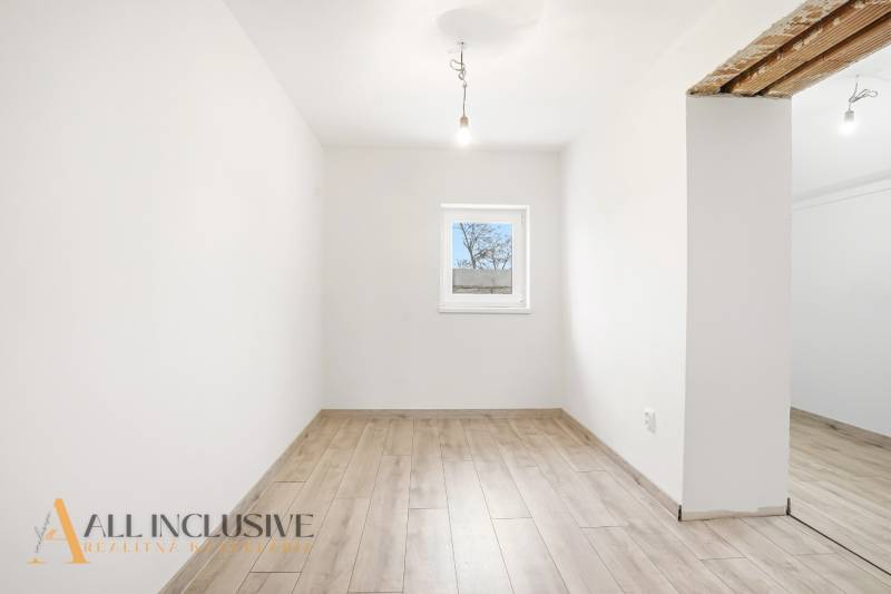 A room in a family house with white walls and a wooden decor floor.