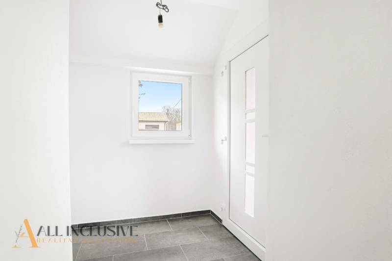 Entrance hall in a family house with a window and light-colored walls, tiled floor.