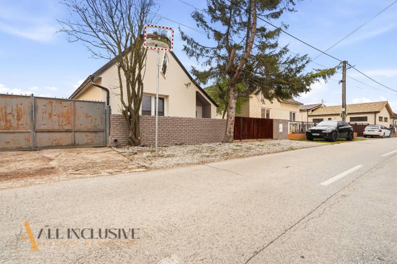 Family houses in Dolný Bar with fencing and parked cars along the road.
