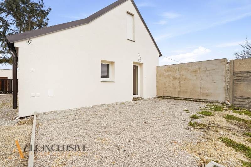 A family house in Dolný Bar with a white facade and a gravel yard.