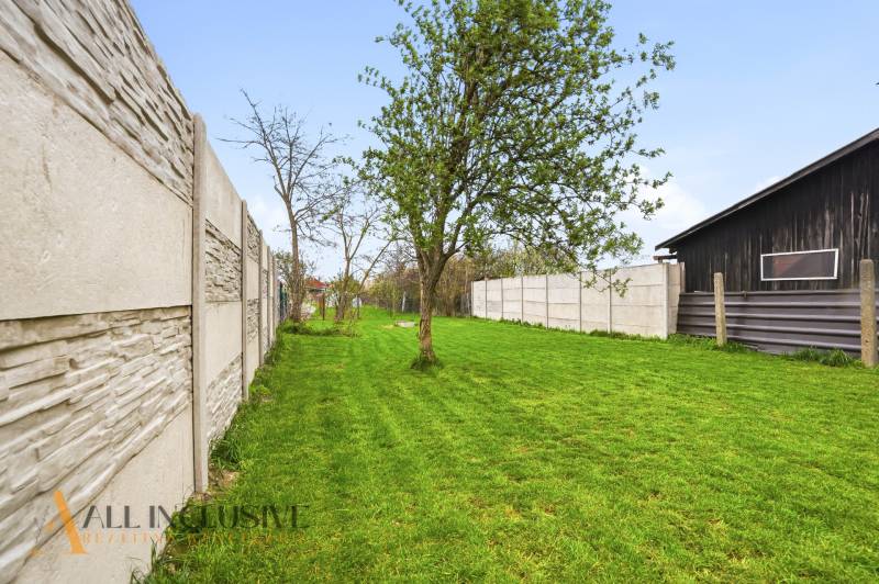 A garden with a lawn and trees in a family house in Dolný Bar, along the fence.
