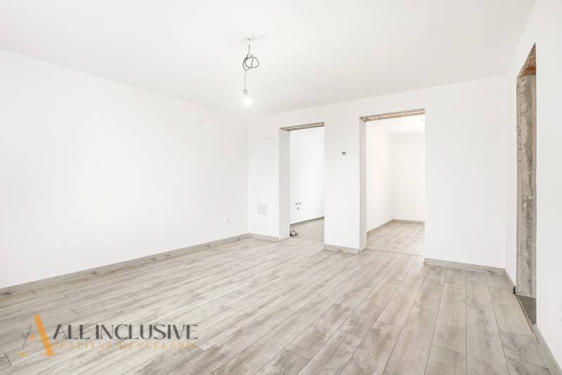 A white room in a family house with a wooden-patterned floor and a bare light bulb.