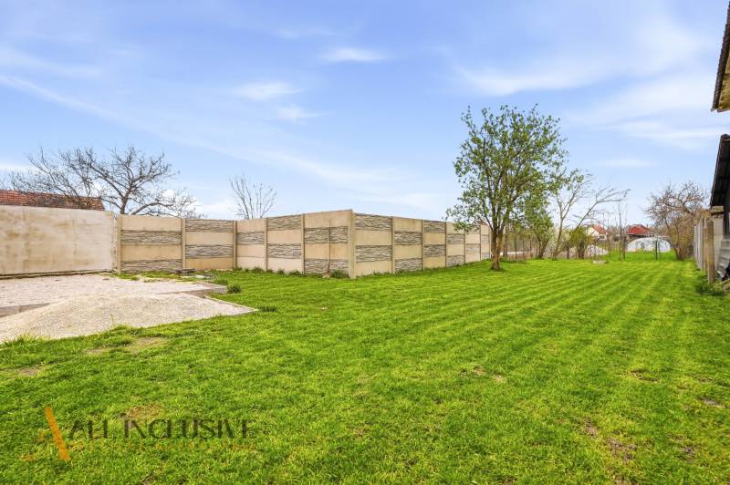The garden of a family house in Dolný Bar with a lawn and a concrete fence.