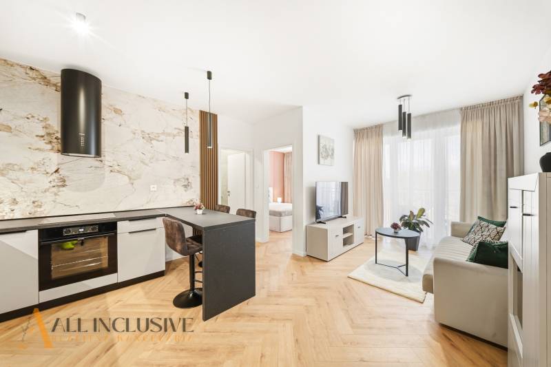 Living room and kitchen in a 4-room apartment with a wooden decor floor and light decoration.