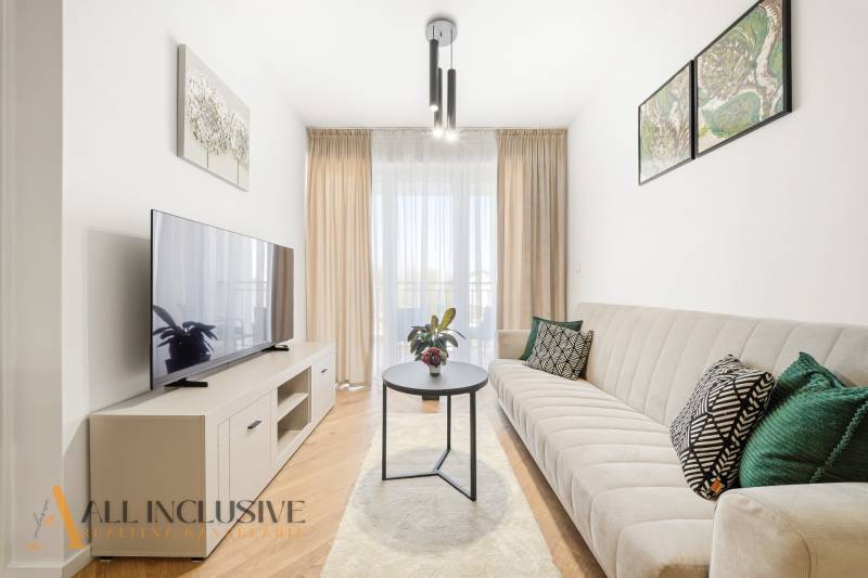 Living room in a 4-room apartment with wood-patterned flooring, light furniture, and a sofa.