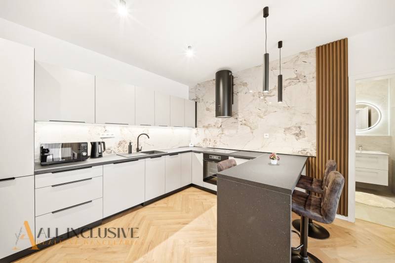 A kitchen with white cabinets, an island, and wood-patterned flooring in a 4-room apartment.