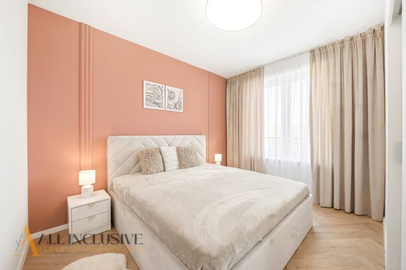 A bedroom with an orange wall and a wooden decor floor in a 4-room apartment.