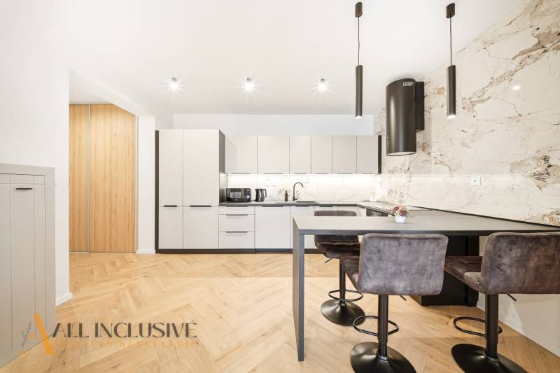 A kitchen in a 4-room apartment with a wooden decor floor and stylish lighting fixtures.