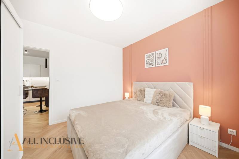 A bedroom in a 4-room apartment with a wood-decor floor and warm tones.
