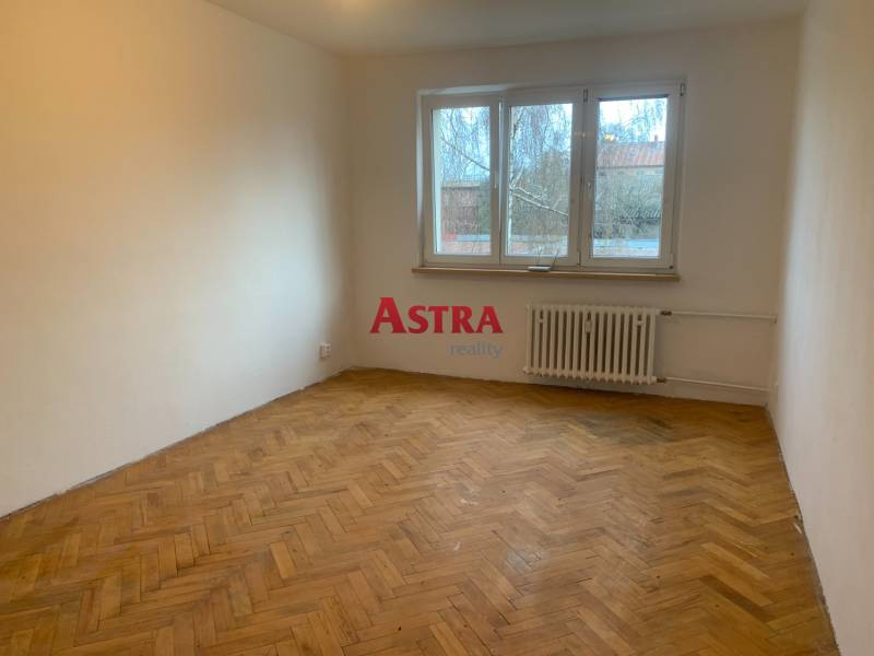 A room in a two-room apartment with a wooden decor floor and a large window.
