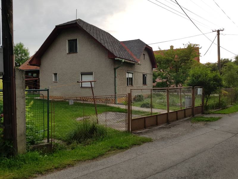 A family house on Blatnica Street in the town of Blatnica with a simple garden and a metal fence.