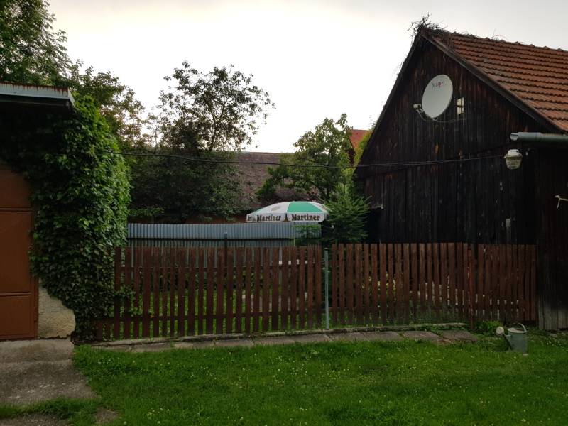 A wooden family house in Blatnica with a wooden fence and a satellite dish.