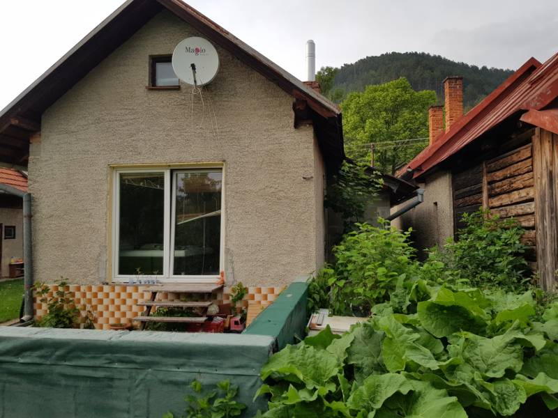 A family house in Blatnica with wooden elements and a garden surrounded by greenery.