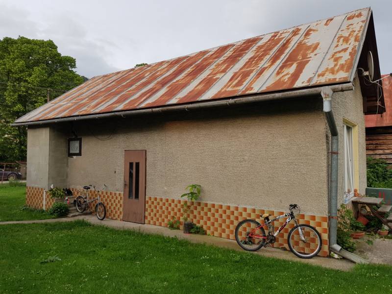 A family house in Blatnica with a metal roof and bicycles in the garden.