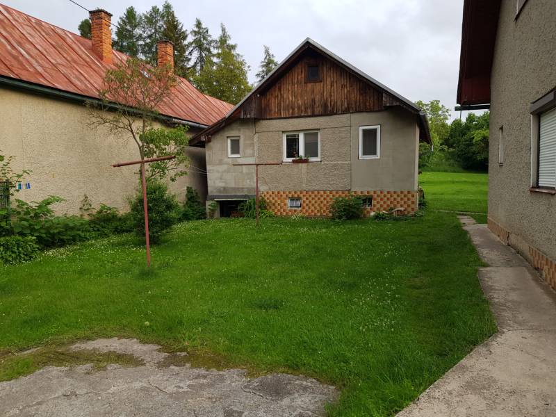 A family house in Blatnica with a front garden and a brick roof, surrounded by green grass.