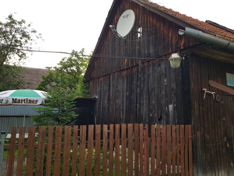 A wooden family house on Blatnica Street in Blatnica with a satellite dish and a lamp.