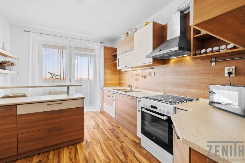A kitchen in a 2-room apartment with a wooden decor kitchen unit and flooring.