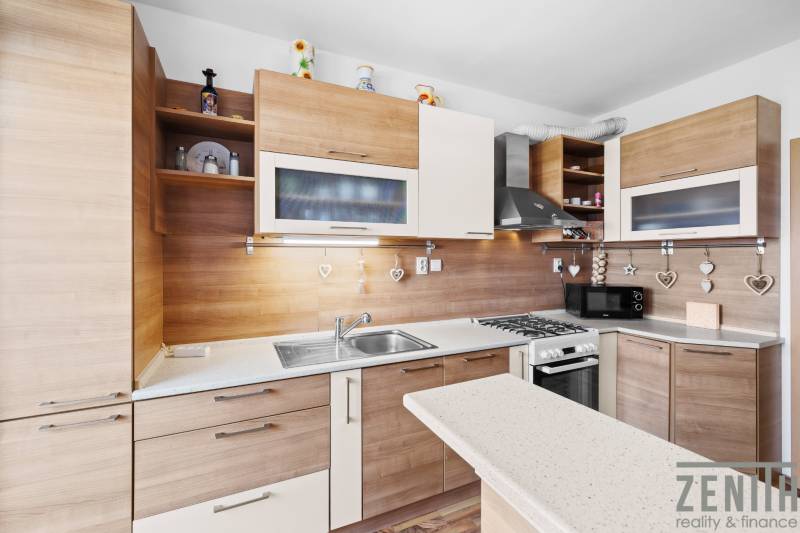 A kitchen in a 2-room apartment with a wooden decor floor and designer lighting.