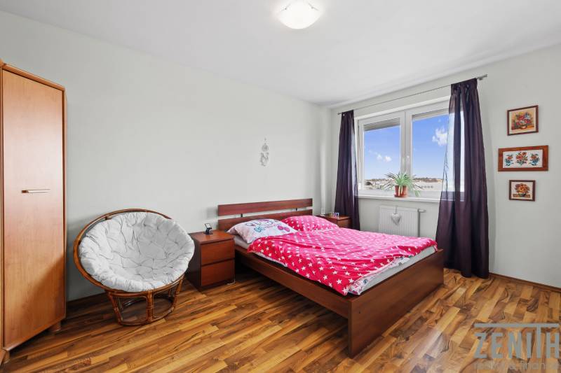 A room in a 2-room apartment with a bed, chair, wardrobe, and floor with a wooden decor.