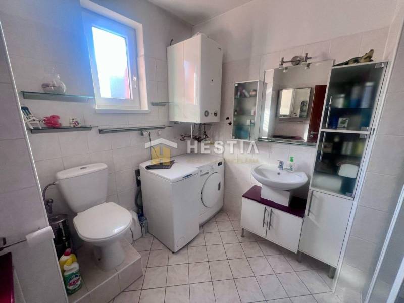 The bathroom in the studio apartment offers a toilet, a washing machine, and shelves by the window.