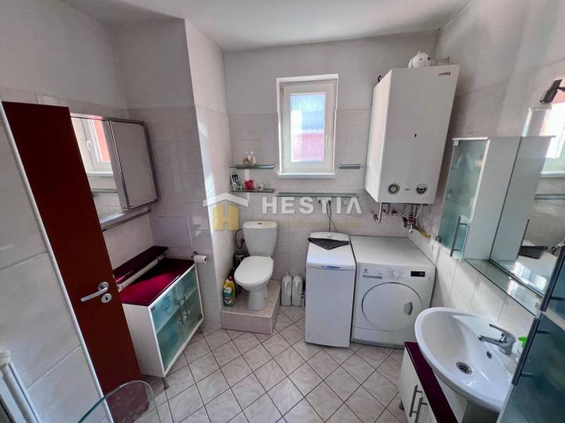 The bathroom includes a washing machine, cabinets, a toilet, and a sink, suitable for a studio apartment.