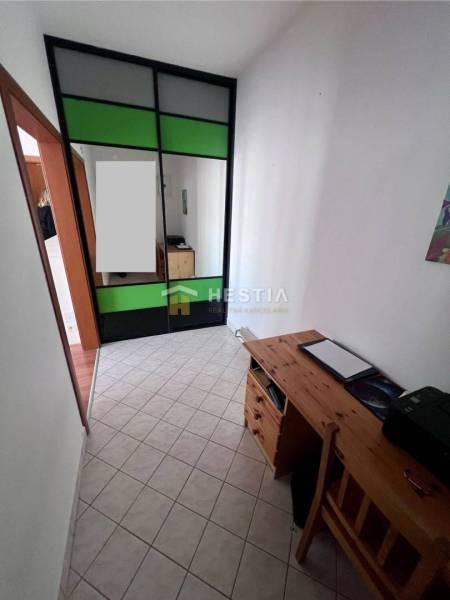 A narrow space with a storage cabinet and a wooden table in a studio apartment.
