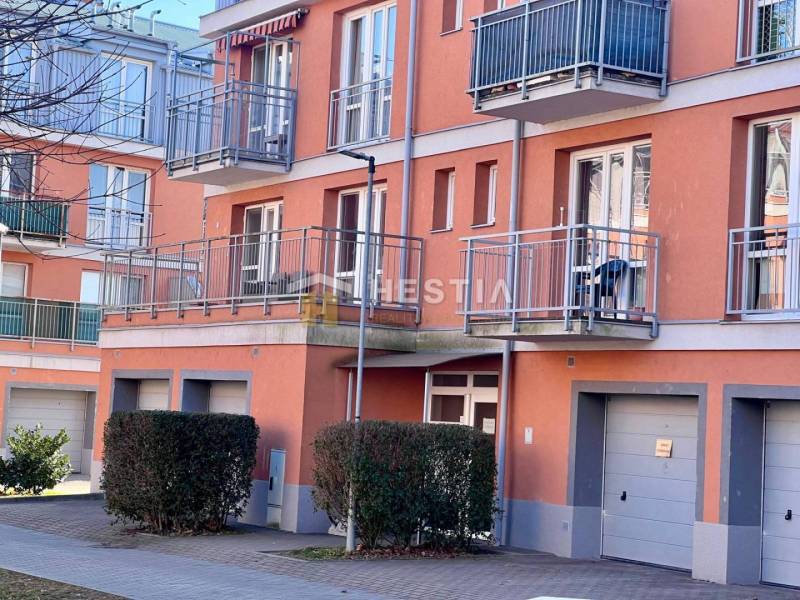 The image captures the exterior of an apartment building with balconies and garages in a one-room apartment.