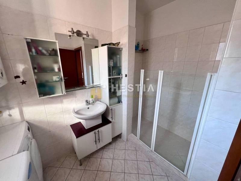 Bathroom with a shower, sink, and storage space in a studio apartment.