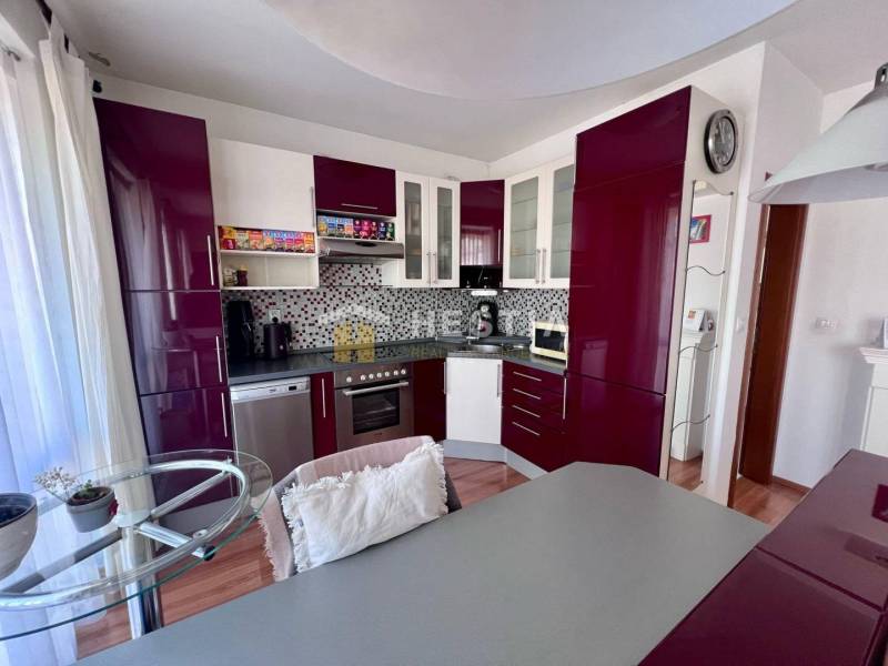 A kitchen with burgundy cabinets in a studio apartment, decorative mosaic tiles on the wall.