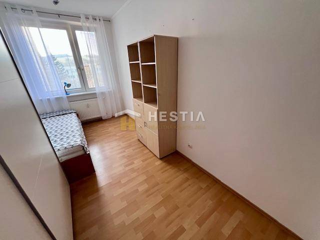2-room apartment, bed by the window, shelf, floor with wood decor, white wall.