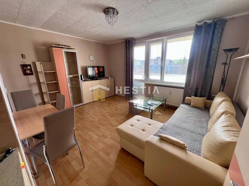 Living room in a two-room apartment with a wood-patterned floor, beige sofa, dining table.