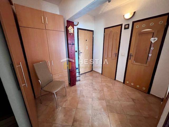 A hallway in a 2-room apartment with tiles, a wardrobe, and a chair.