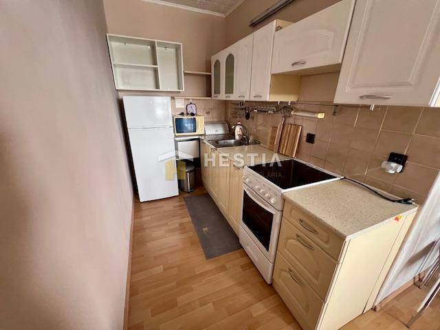 A kitchen in a 2-room apartment with a wooden decor floor and light cabinets.