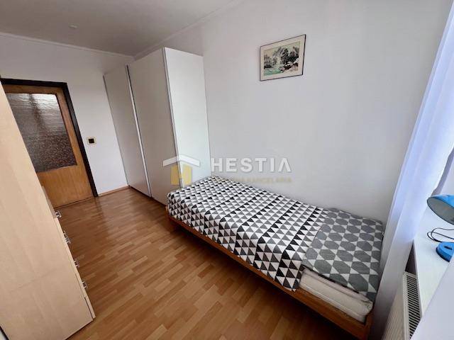 A room in a 2-room apartment with a bed, a wardrobe, and a floor with a wood decor.