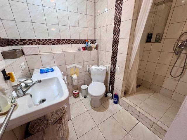 Bathroom in a 2-room apartment with a toilet, shower, and sink.