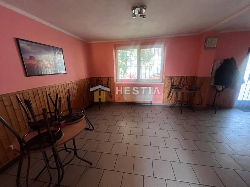 Gastro premises with tiles, pink walls, and stacked furniture.